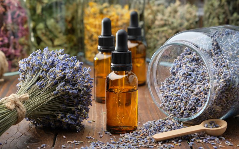 Bouquet de lavande, à côté de fioles en verre brun avec goutte à goutte, à côté d'un grand bocal de verre avec fleurs de lavande sèches.